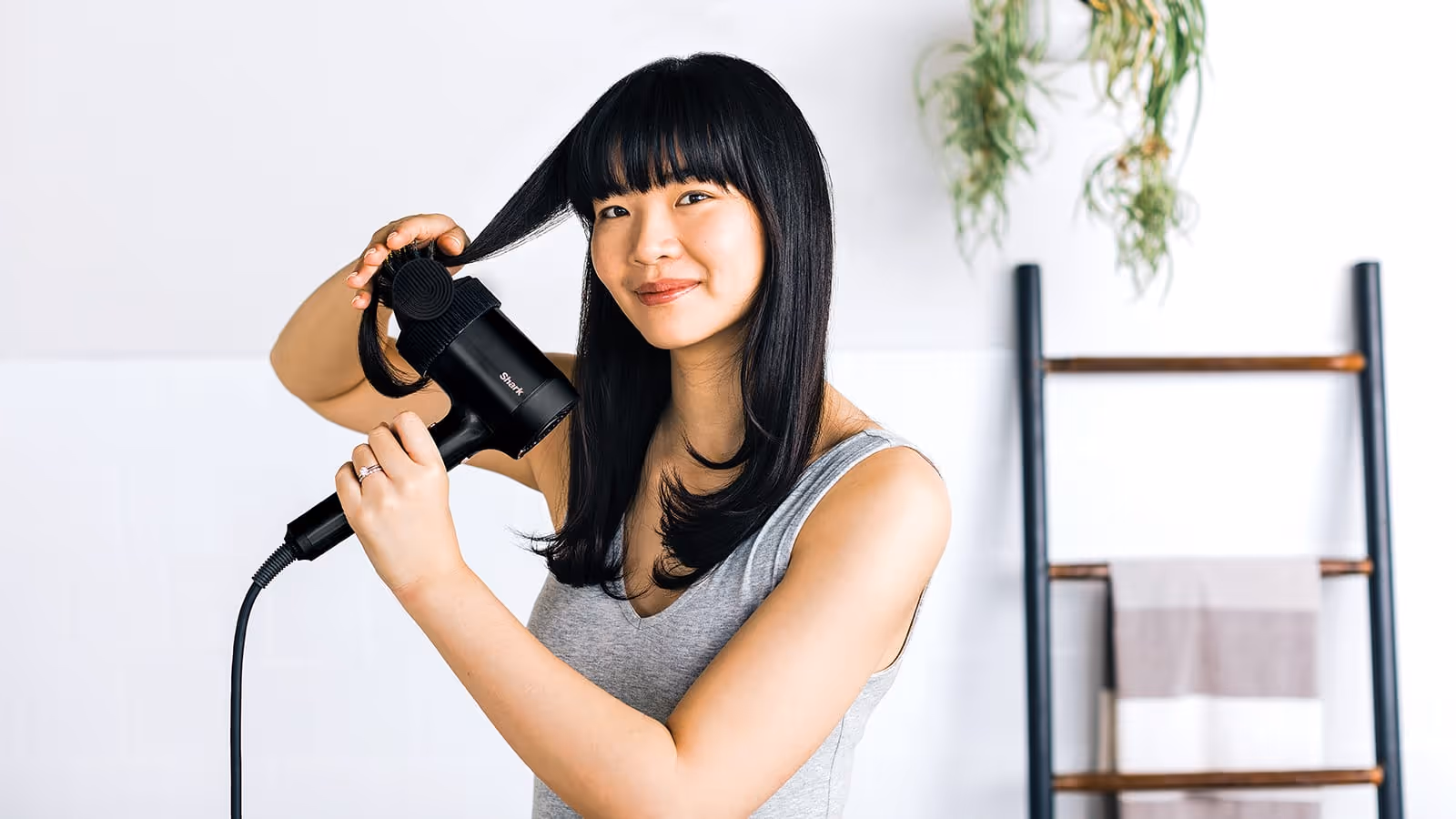 Woman styling her hair with the Shark brush attachment